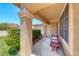 Inviting covered porch with stone pillars, a comfortable bench, and views of the lush front yard at 8914 Termoli St, Las Vegas, NV 89123