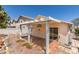Spacious backyard featuring a covered patio, desert landscaping, and mature trees at 9017 Iron Hitch Ave, Las Vegas, NV 89143