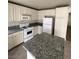 A kitchen featuring granite countertops, tile flooring, white cabinets, and a white refrigerator at 994 River Walk Ct, Henderson, NV 89015