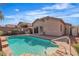 Backyard features a private pool and patio with lush landscaping, a retaining wall, and a house in the background at 11076 Zampino St, Las Vegas, NV 89141