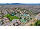 This aerial shot highlights a community pool, tennis courts, and lush green spaces surrounded by beautiful homes at 1172 Strada Pecei, Henderson, NV 89011