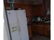 Dated kitchen features wood cabinets, wood wall paneling and a white refrigerator at 1316 Lawry Ave, Las Vegas, NV 89106