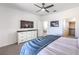 Bright bedroom featuring a ceiling fan, TV, and ensuite bathroom and closet entrances at 187 Palm Fox Ct, Henderson, NV 89011