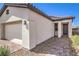 Exterior view of a beige one-story home showcasing desert landscaping and a brick-paved walkway leading to the front door at 187 Palm Fox Ct, Henderson, NV 89011