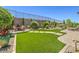 Inviting backyard featuring a manicured lawn, mature trees, and a cozy patio area perfect for entertaining at 2509 Chateau Napoleon Dr, Henderson, NV 89044