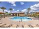 Community pool featuring sun loungers, outdoor tables, palm trees, and clear blue skies at 2509 Chateau Napoleon Dr, Henderson, NV 89044