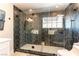 Modern bathroom with a frameless glass shower enclosed with black hexagonal tile and modern fixtures at 2845 Queens Courtyard Dr, Las Vegas, NV 89109