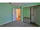 Bright, empty bedroom with light green walls, gray carpeting, mirrored closets and an ensuite bathroom at 2865 Destino Ln, Henderson, NV 89074