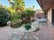 Landscaped backyard features mature trees, stone patio with seating, and small pond at 3167 El Cedro Cir, Las Vegas, NV 89121
