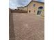 Expansive gravel backyard adjacent to a tan two-story home, featuring a sliding glass door and offering privacy at 3237 Perching Bird Ln, North Las Vegas, NV 89084