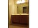 Bathroom featuring warm-toned cabinetry, a sink, a large mirror, and light-colored walls at 3237 Perching Bird Ln, North Las Vegas, NV 89084