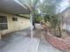 Spacious backyard area with a covered patio, rock bed with brick features and mature trees at 3633 Monte Verde St, Las Vegas, NV 89121