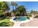 Lush backyard featuring a uniquely shaped pool, mature landscaping, and brick-paved patio at 399 Discovery Ct, Henderson, NV 89014