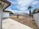 Spacious backyard featuring a concrete patio, perimeter fencing, and a mature palm tree under a blue sky at 4303 Paramount St, Las Vegas, NV 89115