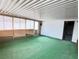 Enclosed sunroom with wood paneling, green carpet, and natural light filtering through the woven shades at 4303 Paramount St, Las Vegas, NV 89115