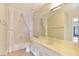 Bright bathroom featuring a vanity with neutral countertops and a shower-tub combo behind sheer curtains at 4687 Madreperla St, Las Vegas, NV 89121