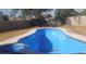 An empty blue in-ground pool sits in a yard with a dark brown wall at 500 Prescott St, Las Vegas, NV 89110
