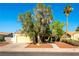 A wide shot of a tan single story home featuring a desert landscape, a driveway, and a two-car garage at 5104 Drummond Rd, Las Vegas, NV 89130