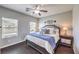 Bedroom with dark wood floors, two windows, a ceiling fan, and a well-decorated bed at 9113 Sea Mink Ave, Las Vegas, NV 89149