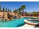 Backyard swimming pool featuring rock waterfall, tropical landscaping, and spa at 231 Bristle Cone, Pahrump, NV 89048