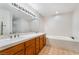 Bathroom featuring a double sink vanity with wood cabinets, large mirror, and a soaking tub at 3629 Laguna Verde Way, Las Vegas, NV 89121