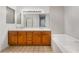 Bathroom featuring a double sink vanity with wood cabinets, large mirror, and a soaking tub at 3629 Laguna Verde Way, Las Vegas, NV 89121