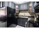 Compact kitchen featuring black appliances, granite countertops, and stylish bamboo accented glass cabinets at 4955 Jeffreys St # 605, Las Vegas, NV 89119