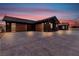 Contemporary single-story home with a dark exterior, tile roof, and a spacious concrete driveway at 6235 N Fort Apache Rd, Las Vegas, NV 89149