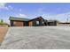 Contemporary black home with unique garage doors and a spacious concrete driveway, blending aesthetics and convenience at 6235 N Fort Apache Rd, Las Vegas, NV 89149