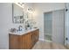 Bathroom with dual sinks, wood cabinets, marble counters, and a large sliding shower door at 7772 Buckwood Ct, Las Vegas, NV 89149