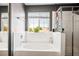 Bright bathroom featuring a soaking tub under a window and glass-enclosed shower at 7820 Esteem St, Las Vegas, NV 89131