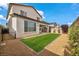 Home exterior with covered patio and large lawn surrounded by landscaping at 9947 Fletcher Peak Ave, Las Vegas, NV 89178