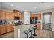 Kitchen island with bar stool seating, wooden cabinetry, and granite countertops at 9947 Fletcher Peak Ave, Las Vegas, NV 89178