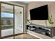 Living room featuring sliding glass doors to the back yard and a wall-mounted television with floating shelves at 9947 Fletcher Peak Ave, Las Vegas, NV 89178