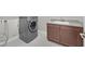 Modern laundry room featuring gray front load washer, sleek cabinetry, and light tile flooring at 2170 Monte Bianco Pl, Henderson, NV 89044