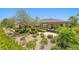 Landscaped backyard featuring mature trees, manicured shrubbery, and a stone patio with seating at 3048 Red Arrow Dr, Las Vegas, NV 89135