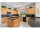 Spacious kitchen featuring granite countertops, wood cabinetry, and a central island with breakfast bar at 3048 Red Arrow Dr, Las Vegas, NV 89135
