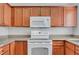 A well-lit kitchen features wooden cabinetry, granite countertops, and modern white appliances at 4400 S Jones Blvd # 1125, Las Vegas, NV 89103