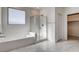 Bright bathroom showcasing a soaking tub, glass-enclosed shower, and neutral tile floors at 532 Monarch Ridge Ct, North Las Vegas, NV 89084
