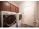 Functional laundry room with wooden cabinets and updated washer and dryer units at 7252 Blowing Breeze Ave, Las Vegas, NV 89179