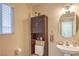 Neutral bathroom with white sink, vanity, mirror, wooden storage cabinet, and toilet at 8737 Autumn Valley Ave, Las Vegas, NV 89129