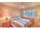 A carpeted bedroom with a ceiling fan, neutral color tones, natural light, and a view of palm trees at 8737 Autumn Valley Ave, Las Vegas, NV 89129