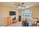 A carpeted bedroom featuring a ceiling fan, natural light, and a view of palm trees at 8737 Autumn Valley Ave, Las Vegas, NV 89129