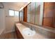 Bright bathroom featuring double sinks, full mirror, wood accents and a shower over tub combination at 860 Bergamont Dr, Henderson, NV 89002