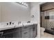Modern bathroom featuring a dual sink vanity with a white countertop and a glass-enclosed shower with geometric tile at 108 Parker Ranch Dr, Henderson, NV 89012