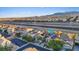 This aerial view showcases a vibrant community with solar panels near a highway and distant mountains at 8325 Winterchase Pl, Las Vegas, NV 89143