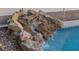 Poolside rock waterfall feature with water cascading into a sparkling blue pool at 8325 Winterchase Pl, Las Vegas, NV 89143