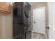 This modern laundry room includes a black stacked washer and dryer and a white door to the outside at 8929 Monte Oro Dr, Las Vegas, NV 89131