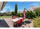Backyard patio with red table, green grass, a hammock, mature trees, and ample privacy offers a perfect outdoor retreat at 2093 Seahurst Dr, Las Vegas, NV 89142