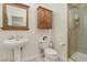Bathroom with pedestal sink, toilet, and glass shower with wood accent cabinet at 613 Pinnacle Heights Ln, Las Vegas, NV 89144